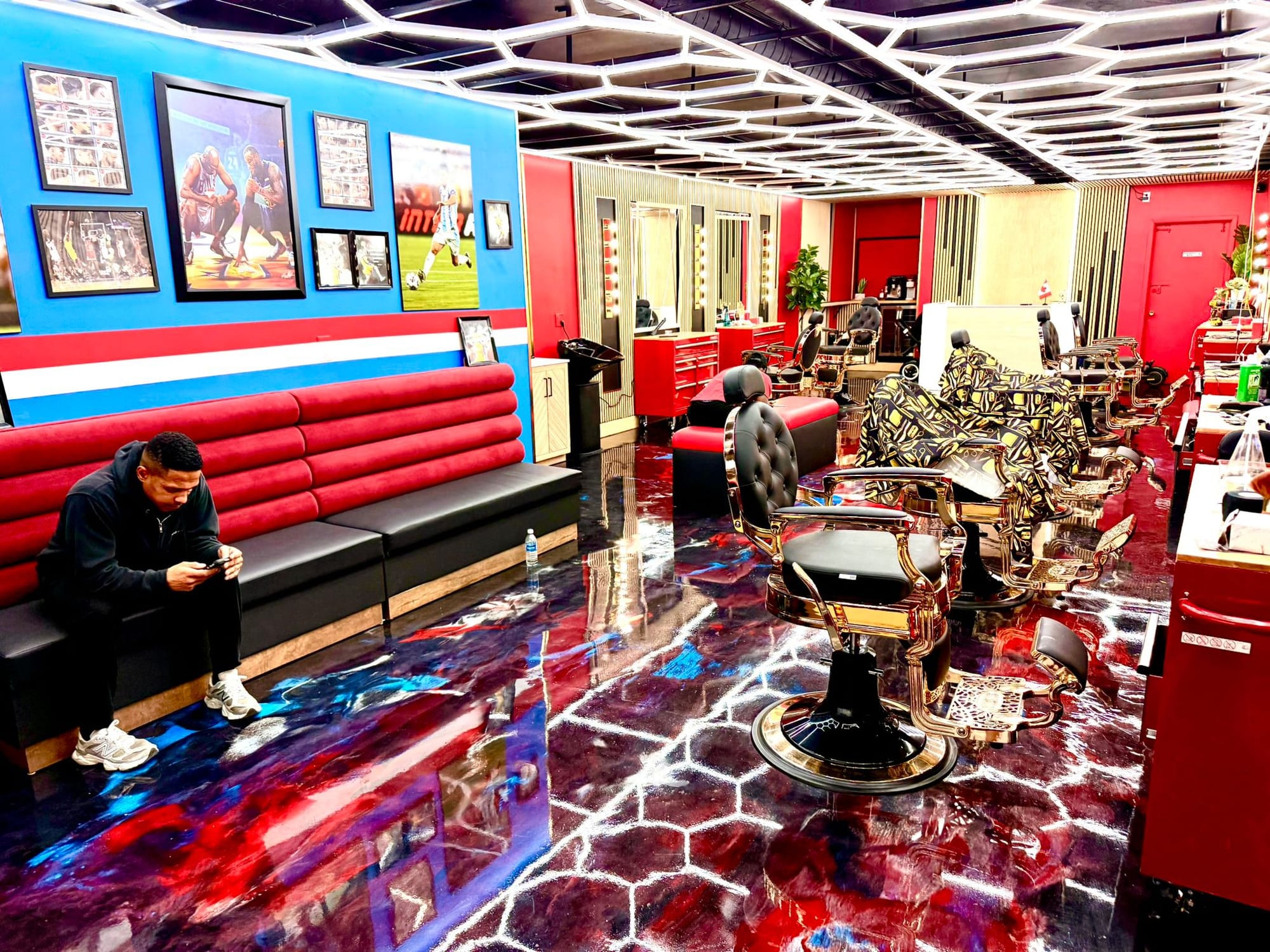 Inside the Weston Road shop — hexagon LED ceiling, red leather benches, gold barber chairs on a marbled epoxy floor